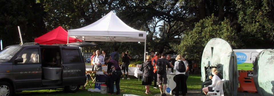 People serving a free breakfast from a marquee next to a van in a park